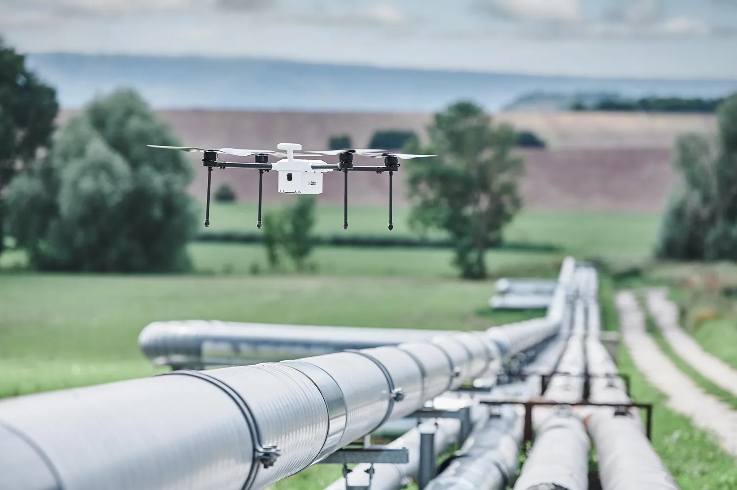Zelos drone hovers over a pipeline running through an uninhabited landscape.